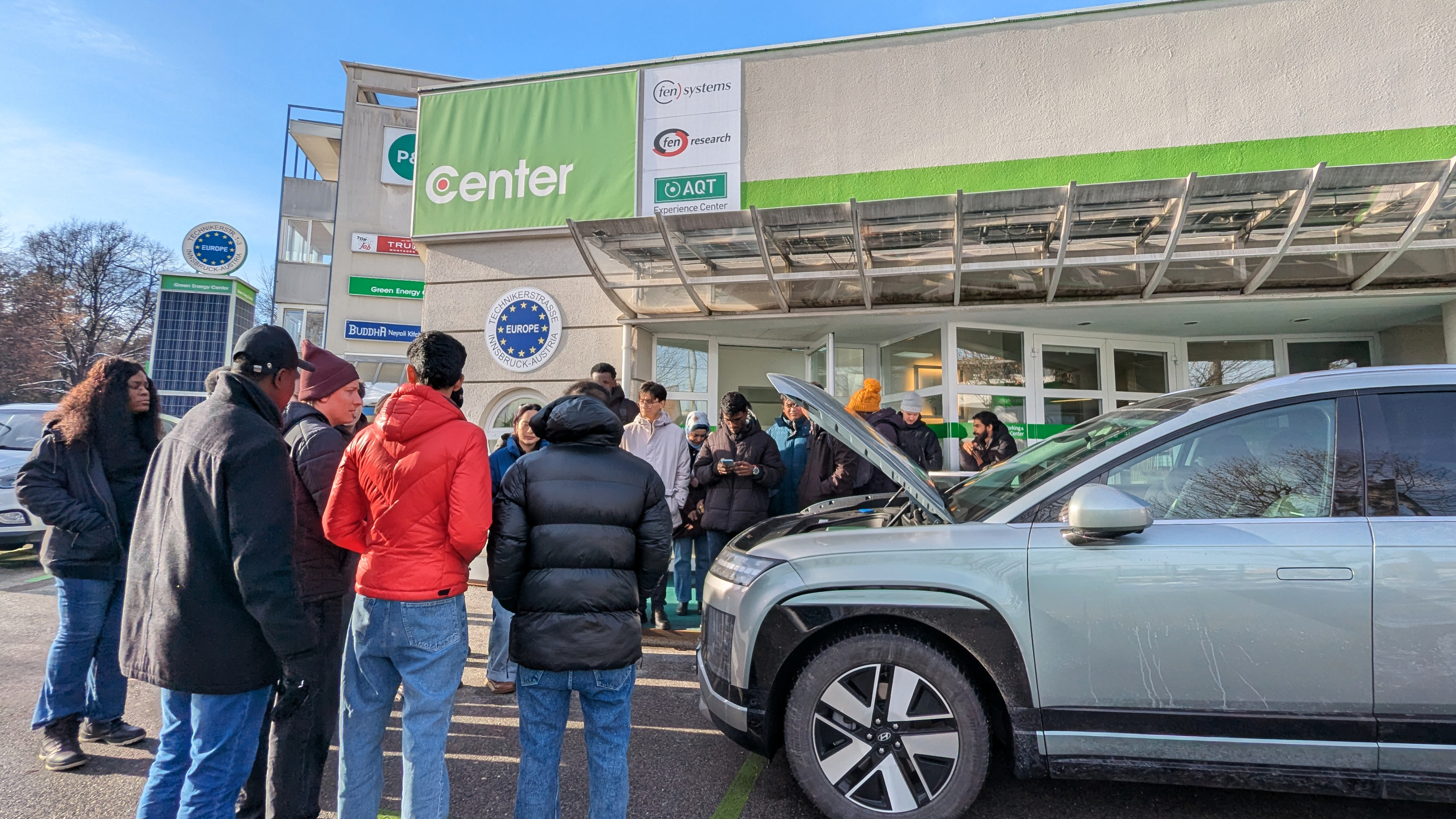 Students standing outside observing the front of a car demonstrating green energy