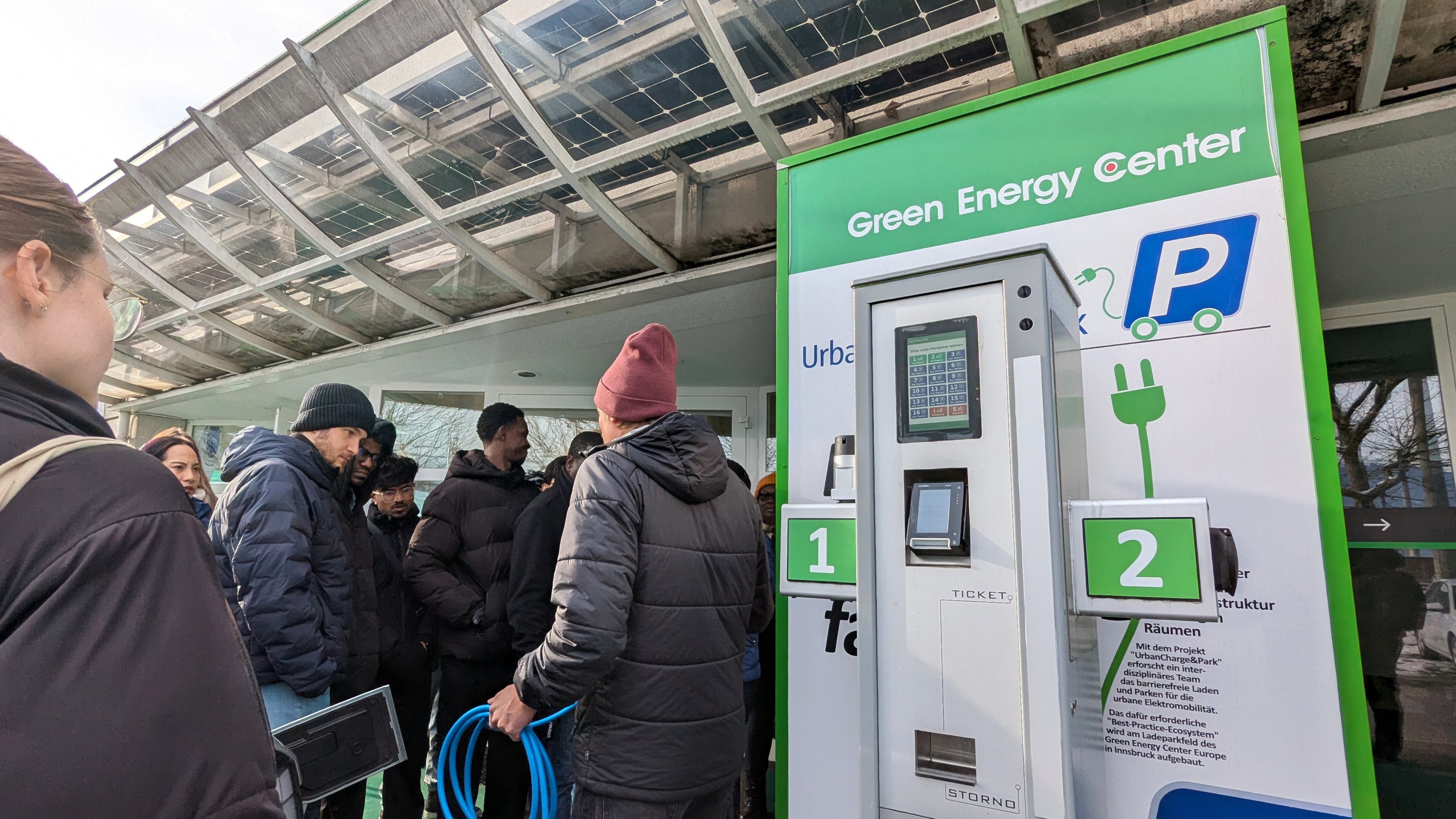 Students standing outside examining how a car charges using green energy