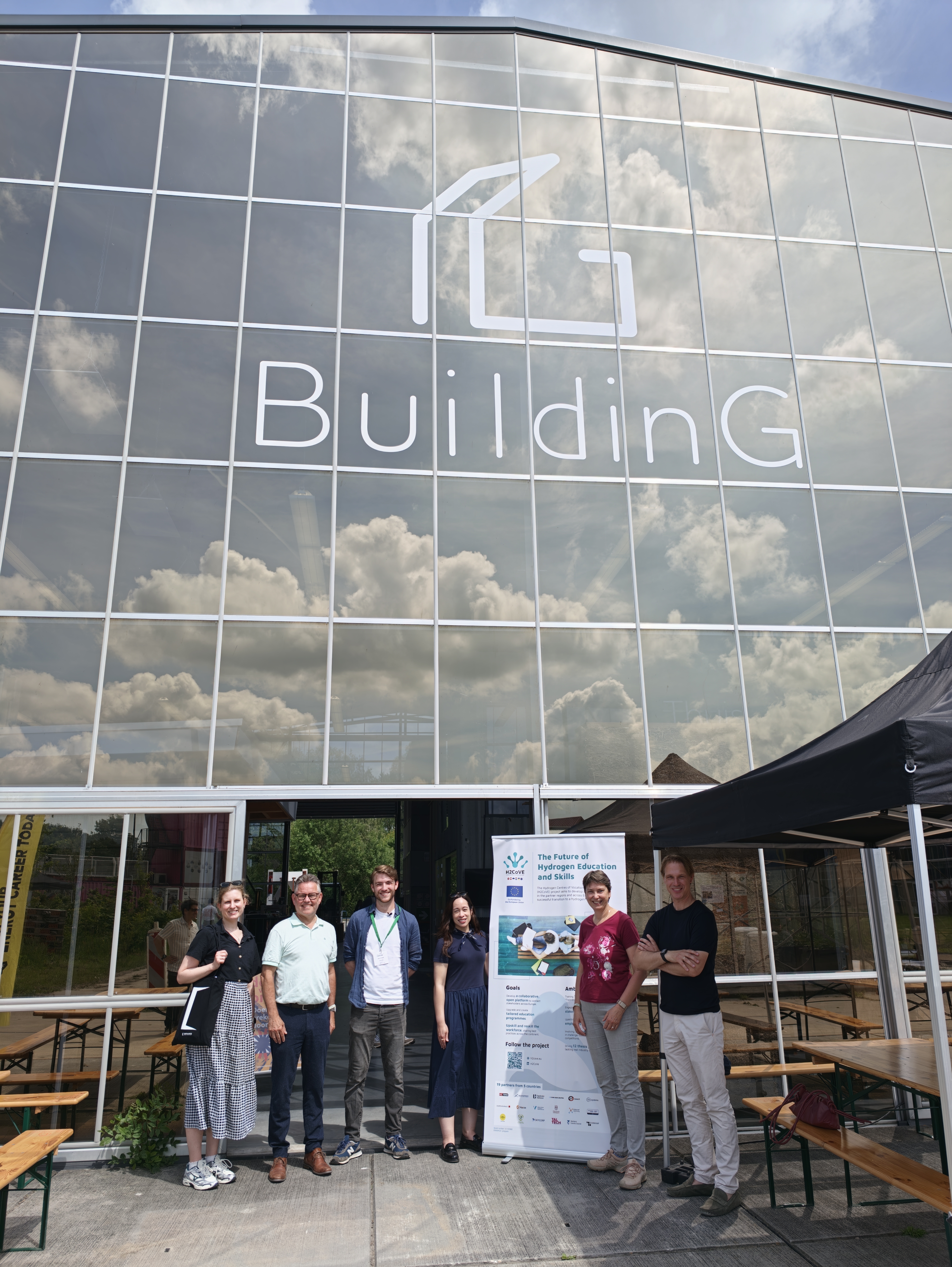 H2CoVE project partners standing in front of the forum venue with an H2CoVE roll-up banner