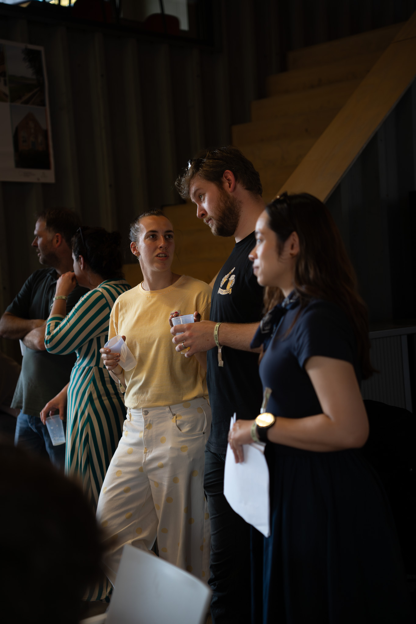 Five forum participants, including an H2CoVE project partner, standing at the back of the room and netweorking with one another.